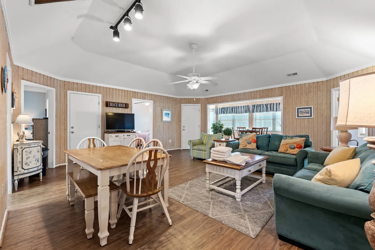 A cozy, inviting living and dining area featuring a large dining table, a comfortable seating area with a couch, a television unit, and carefully chosen decorative accents. The scene is set for shared activities, from meals to game nights, with soft lighting and thoughtful decor enhancing the welcoming atmosphere.
