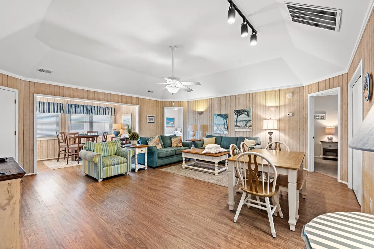 A view of a plush seating area and dining table, with decorative wall art lending a homey touch. The arrangement and styling suggest a space designed for both intimate and lively gatherings, inviting guests to relax, dine, or celebrate special moments together.